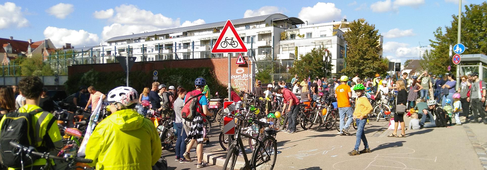 Auf der Brücke der Hochfeldstraße über die Bahnlinie stehen Fahrräder und Menschen, die meisten mit Helm. Es gibt Kreidezeichnungen auf dem Asphalt und Luftballons. Die Menschen stehen zwischen ihren Fahrrädern und unterhalten sich.